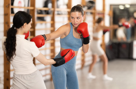 Young girl training boxing with partner during sports classes