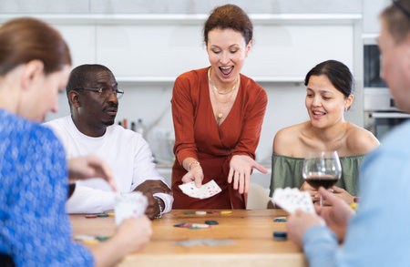 Joyful middle-aged men and women playing poker at home