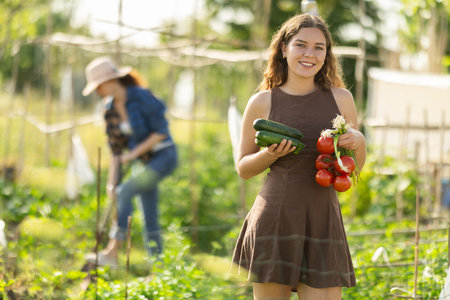 Young woman with vegetable harvest in cottage garden