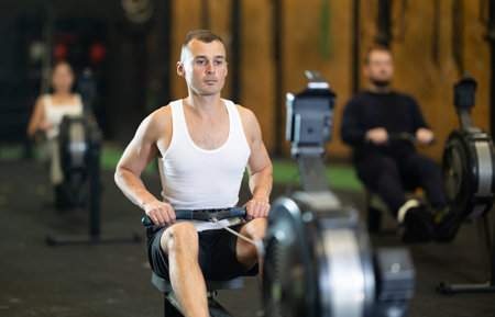 Man exercising on rowing machine during high intensity workout