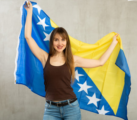 Smiling woman waving flag of Bosnia and Herzegovina in studioの写真素材
