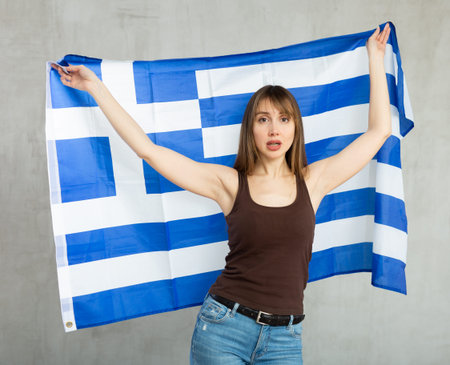 Young pretty woman displaying flag of greeceの写真素材