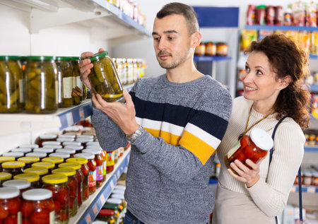 Couple man and woman choose pickled cucumbers and tomatoesの写真素材
