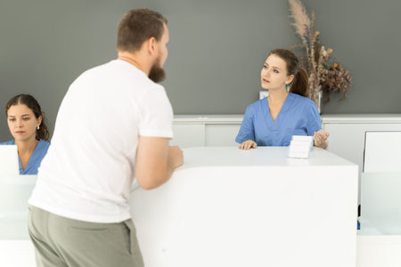 man is standing near the reception in the dentistry and asks about an appointment with a dentistの写真素材