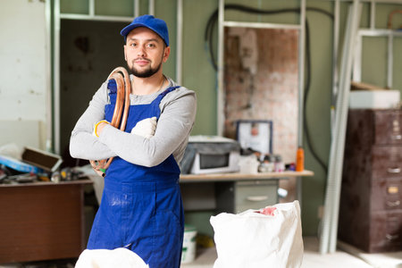 Portrait of a young builder with a coil of heating cable