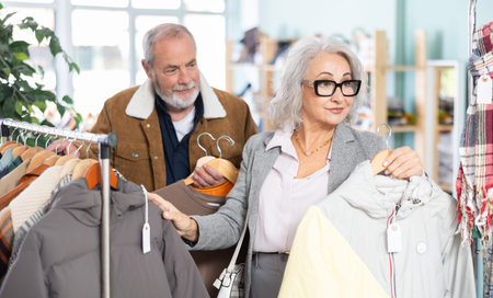 Mature couple spend time in shop and choose down jacket and T-shirt