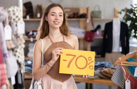 Portrait of woman holding sign saying 70 percent discount in clothing store