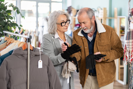 Elderly husband and wife chooses warm gloves in clothing storeの写真素材