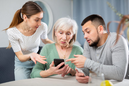 Adult children help an elderly mother learn how to use smartphone
