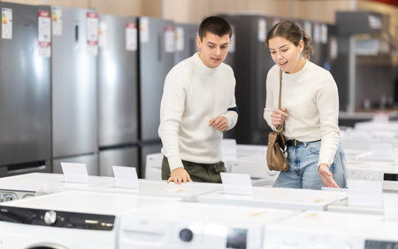 Young couple choosing washing machine or dishwasherの写真素材
