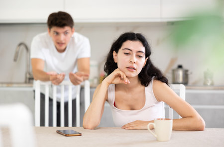 Young guy quarrels with young woman in kitchen
