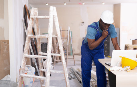 Portrait of a male builder who checks work done using a laptop