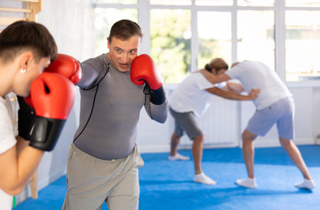 Two athlete men in sportswear practicing boxing sparring in hall