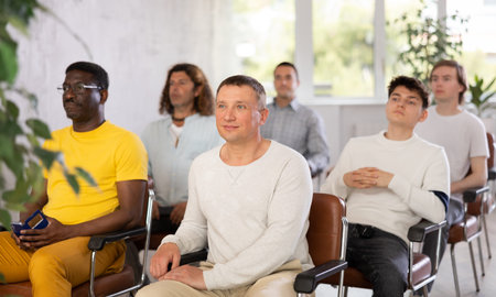 Group of men listening to lecture in auditorium attentively
