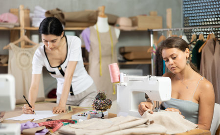 Two clothing makers working on sketches and stitching