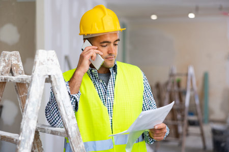 Man builder having telephone conversation in construction site