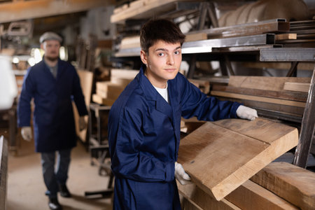 Preparing for furniture production - furniture factory worker places a board on cutting machine