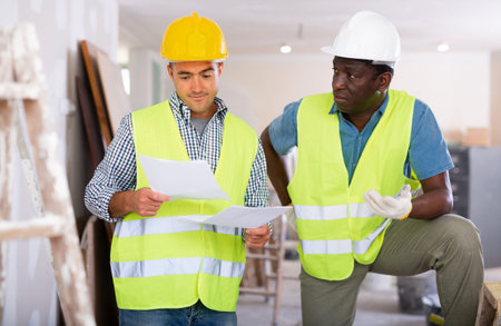 Builders having conversation about work plan in apartment