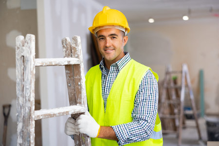 Portrait of positive man repairer with stepladder