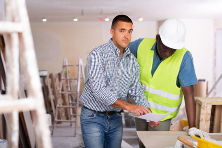 Owner of cottage discusses with worker drawings of room being repaired