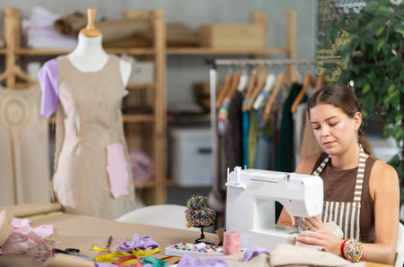 Female seamstress working on a machine against the background of a mannequin