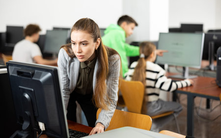 Teacher using personal computer during lesson in school