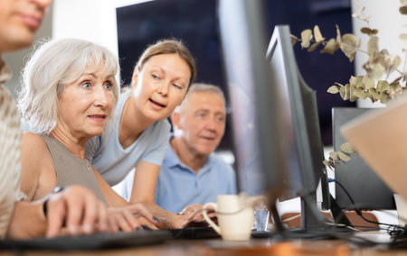Woman teacher helping elderly people learn how to use computer