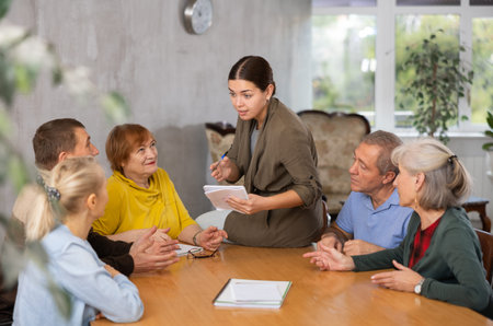Young psychologist together with elderly adults have group therapy round table