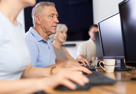 Elderly man studying at computer course in group