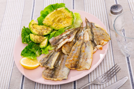 Fried cod fillet is guaranteed with salad of spinach leaves and avocado slices
