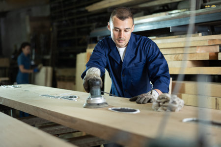 Man sanding a wooden board using sanding machine