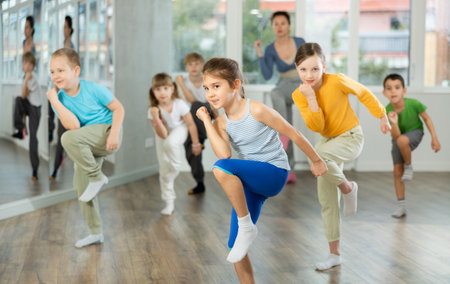 Group of preteen girls and boys enjoying active dance movement in studio