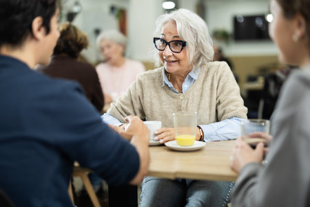 Large family is having breakfast in a cozy cafe, discussing news.