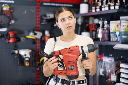 Woman buys electric perforator, collect necessary supplies in store according to list for repairs