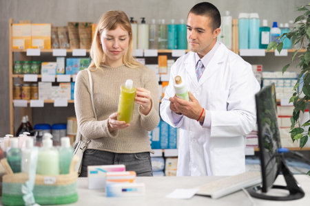 In sales area, girl examines antidandruff shampoo, man pharmacist in backgroundの写真素材