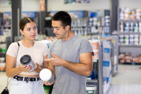 Spouses buyers with cans of paint in hands choice and closely examines product, enamel dyeの写真素材