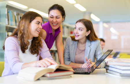 Three female friends studying together at library