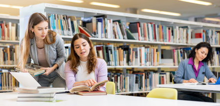 Two women friends studying together at library