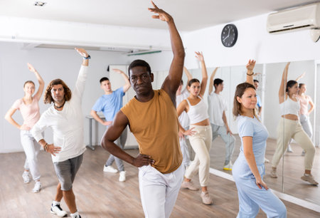 Group of happy young adult multinational sports people exercising dancing in modern gym studio