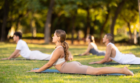 Girl performing Cobra Pose during group yoga training in park
