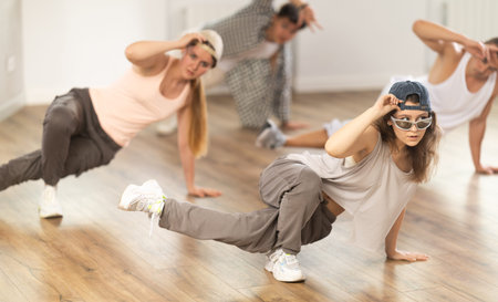Concentrated guys and girls studying movement of contemporary dance in classroom with his friends