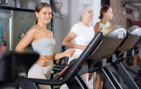 Focused motivated girl leading healthy active lifestyle doing cardio workout in gym, running on...