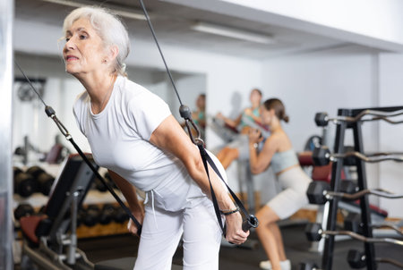 Elderly woman training her arms using straps