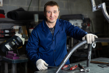 Experienced middle-aged worker posing in professional metalworking workshop