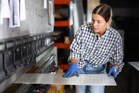 Young woman bends sheet of metal under pressureの写真素材