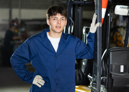 Young male worker working on forklift at metallurgical plant