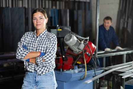 Portrait of positive female worker in workshop of metallurgical plant