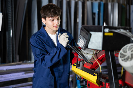 Young guy cuts profile pipe on machine
