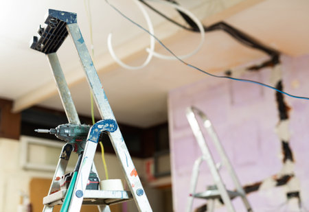 Interior of room being repaired with stepladder and wires