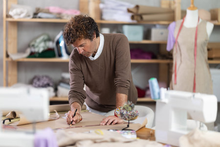 Man drawing on paper in sewing workshop